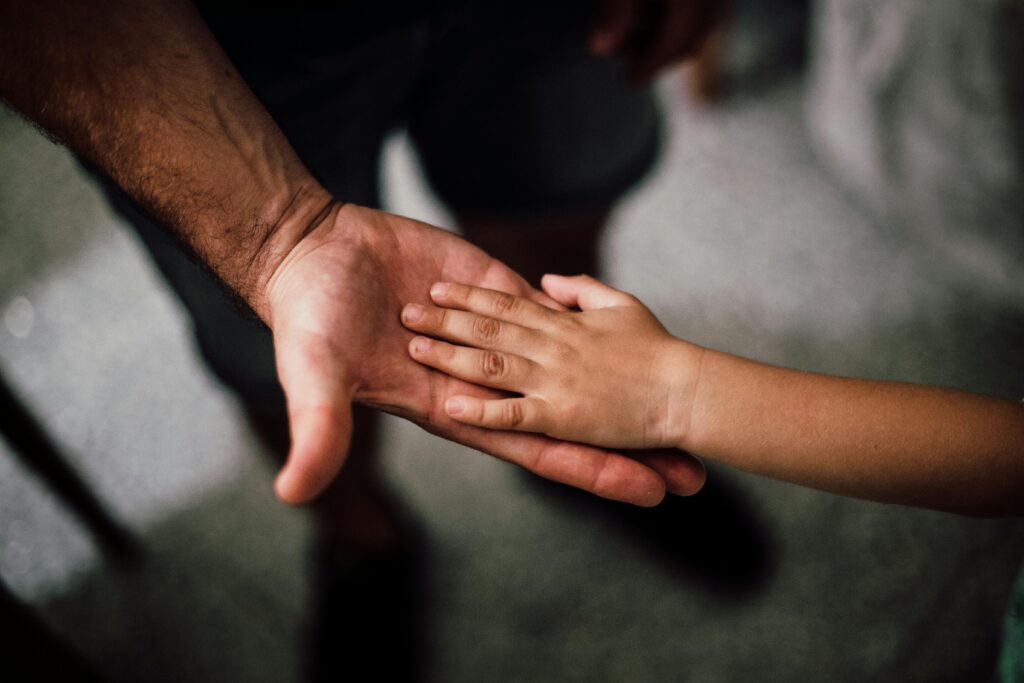 Close-up of a child's hand resting gently on a man's hand, symbolizing love and support.