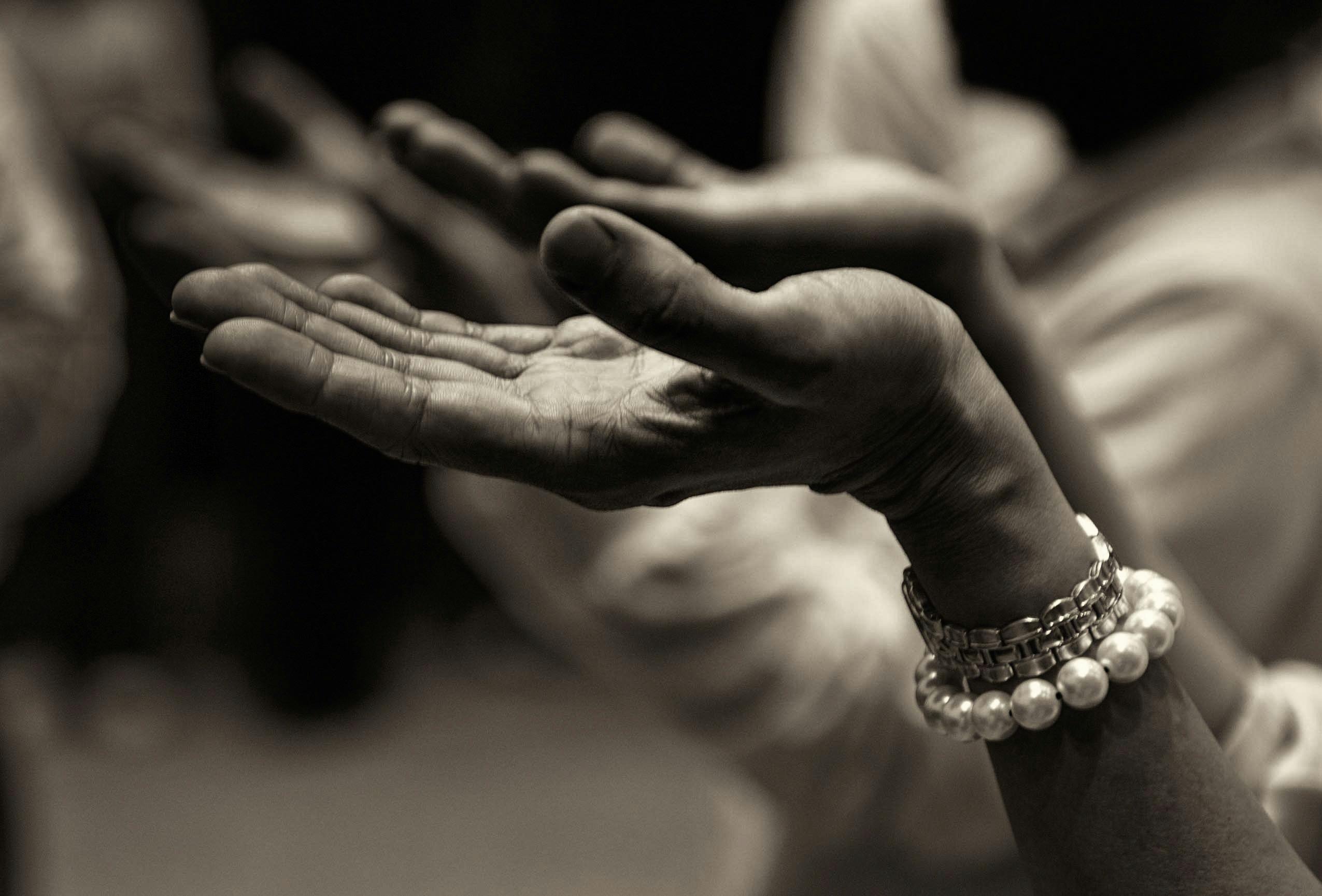 Close-up of expressive hands in prayer wearing a bracelet, conveying faith and devotion.