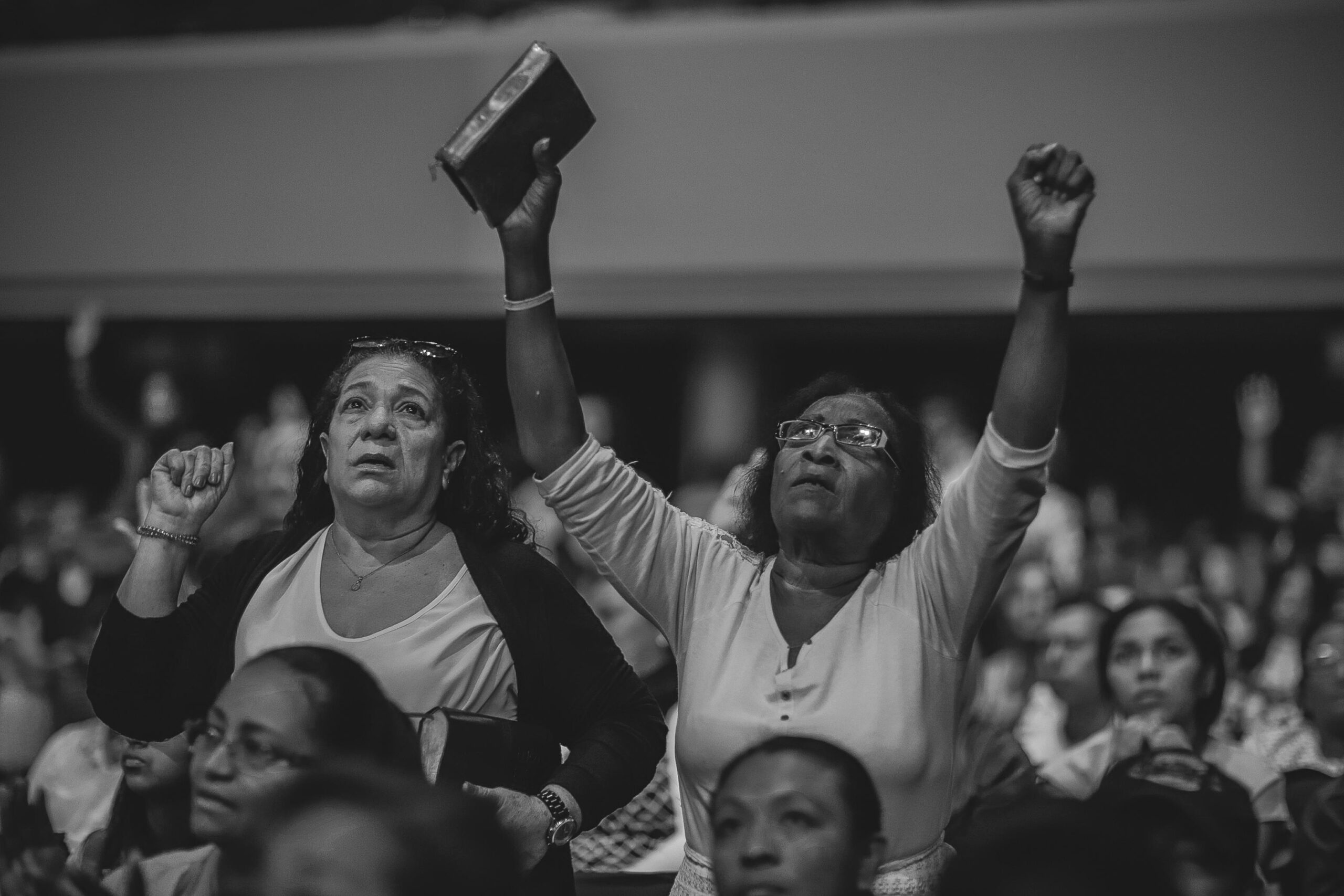 A heartfelt moment of worship in a crowded indoor religious gathering.