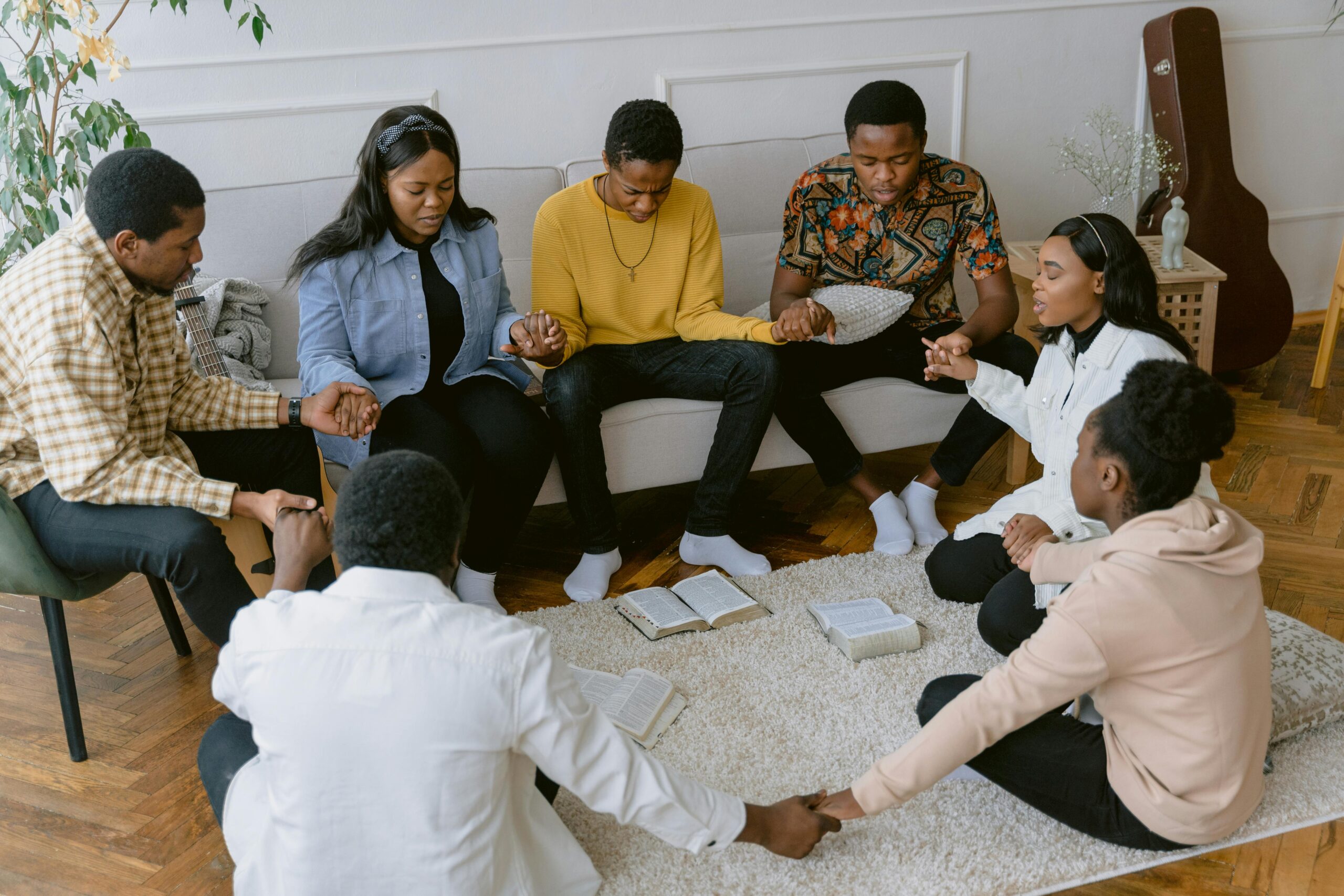 A group of people holding hands in prayer, creating a sense of unity.